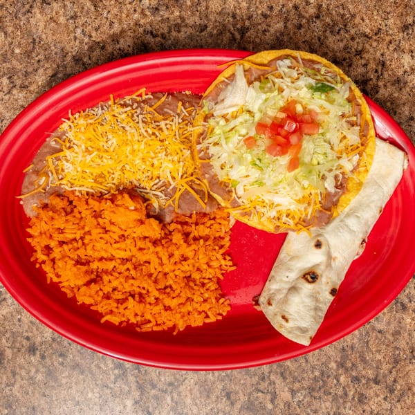 A red plate holds a Mexican meal with rice, beans, a tostada, and a burrito.